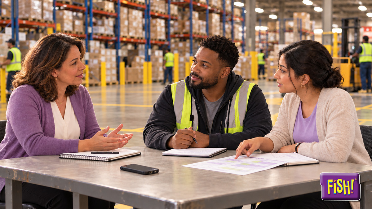 Manager meeting with a warehouse operations lead and a planner at a table in a distribution center to plan weekend coverage, FISH! Philosophy